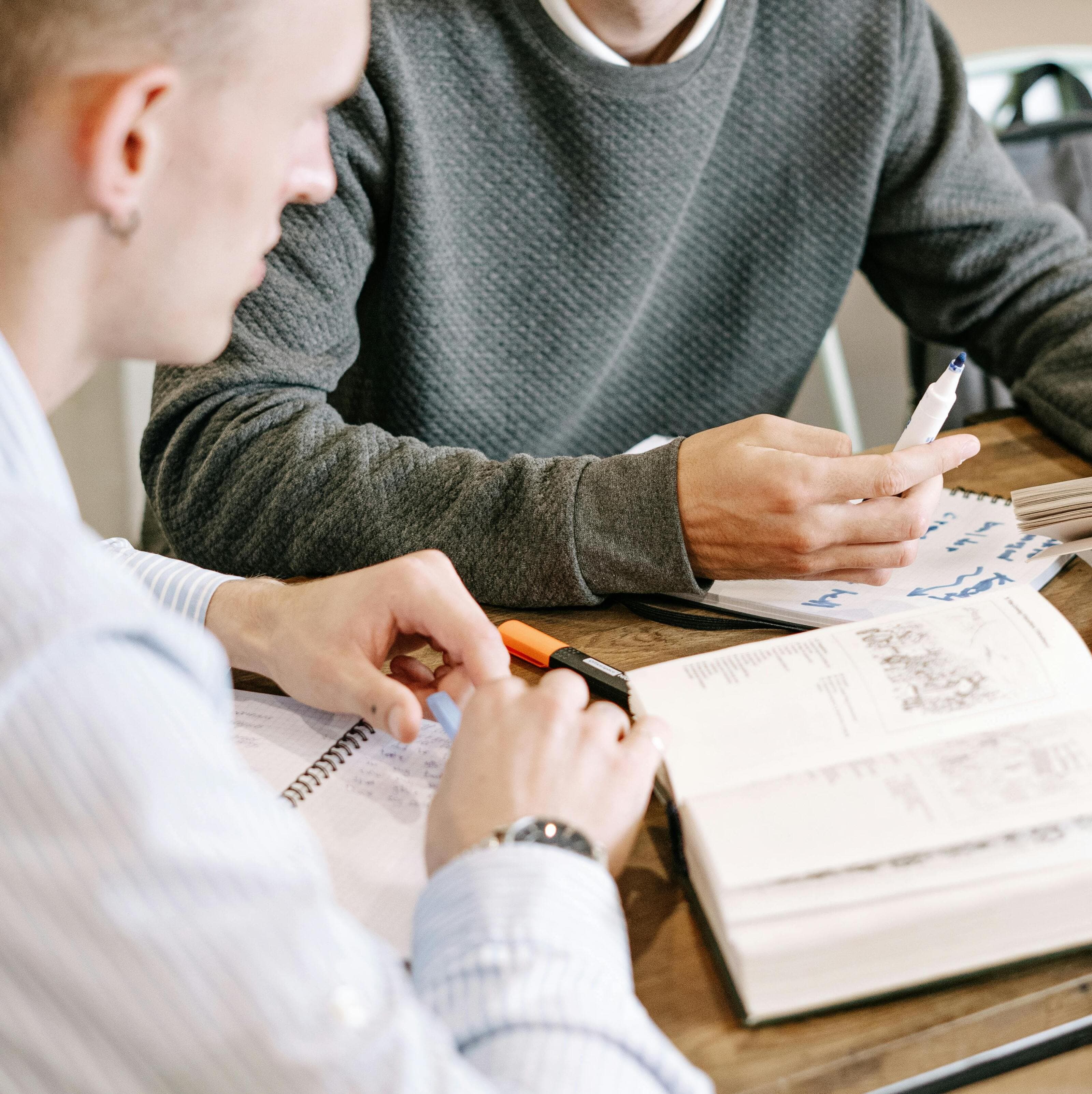 student and tutor working together at desk with book open
